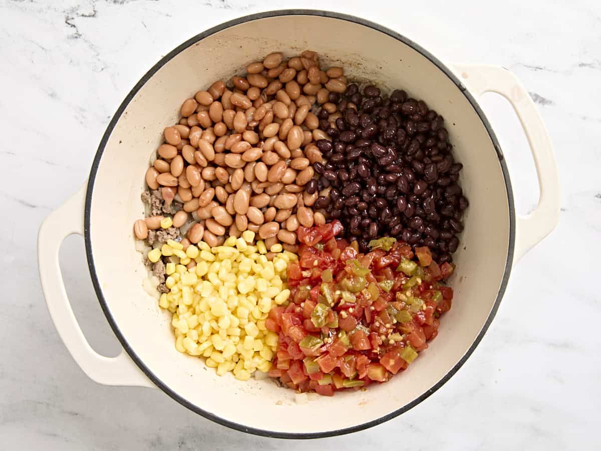 Beans, diced tomatoes, and frozen corn added to a dutch oven to make taco soup.