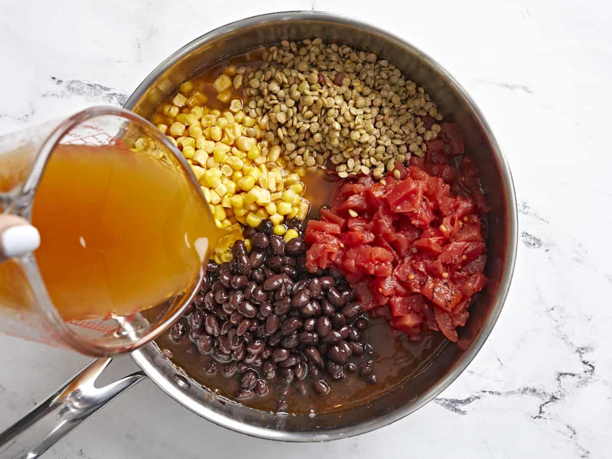 Lentils, fire-roasted tomatoes, black beans, corn, and vegetable broth added to the skillet.