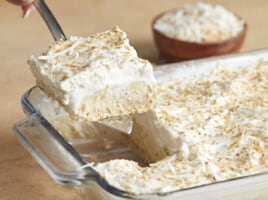 Side view of coconut cream pie bar being lifted out of the casserole dish.
