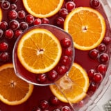 Close up overhead view of a punch bowl full of Christmas Punch with oranges and cranberries.