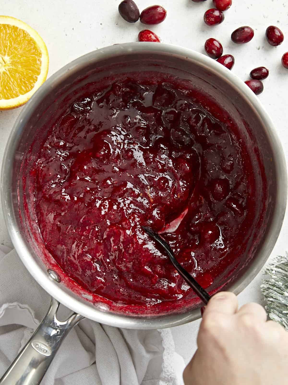 Overhead view of a pot full of homemade cranberry sauce being stirred.