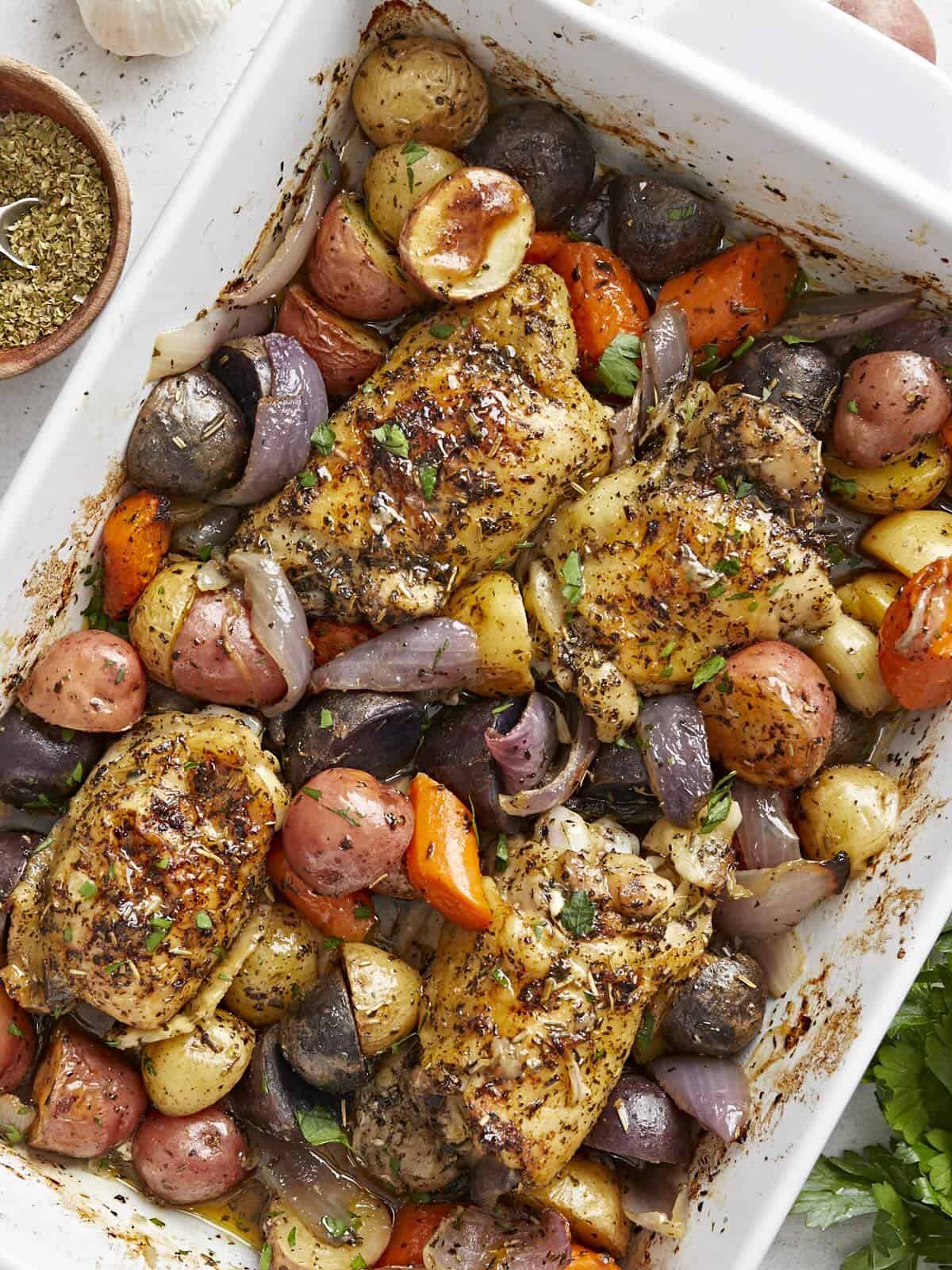 Overhead view of a large white casserole dish filled with roasted chicken and vegetables.