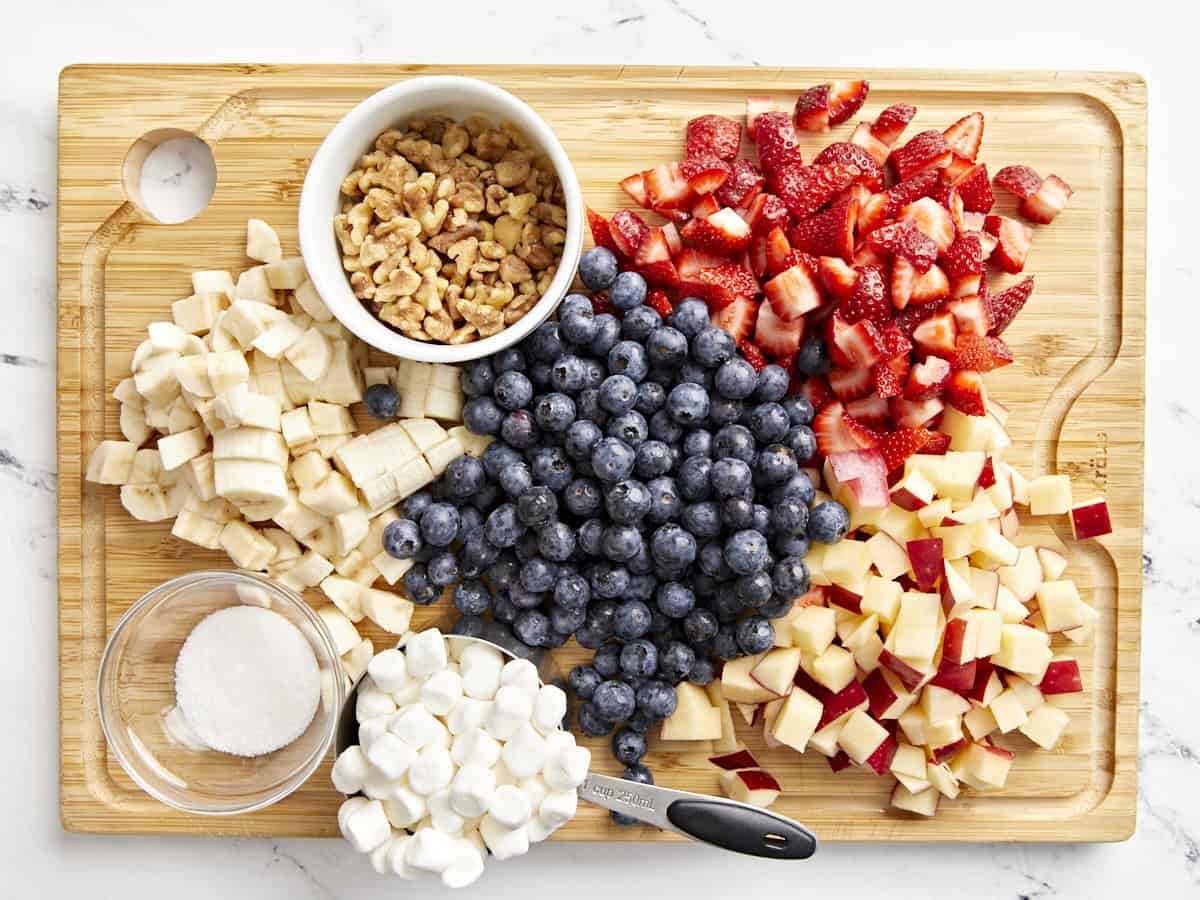 ingredients for red white and blue fruit salad on a cutting board.