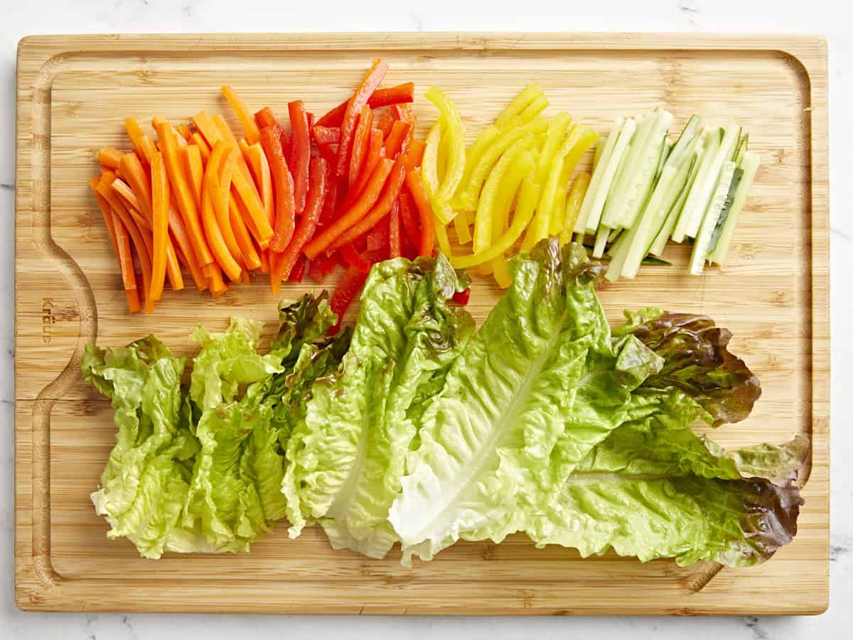 julienned veggies and lettuce on a cutting board.