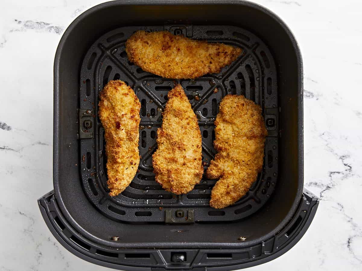 Overhead view of cooked air fryer chicken tenders in an air fryer basket.
