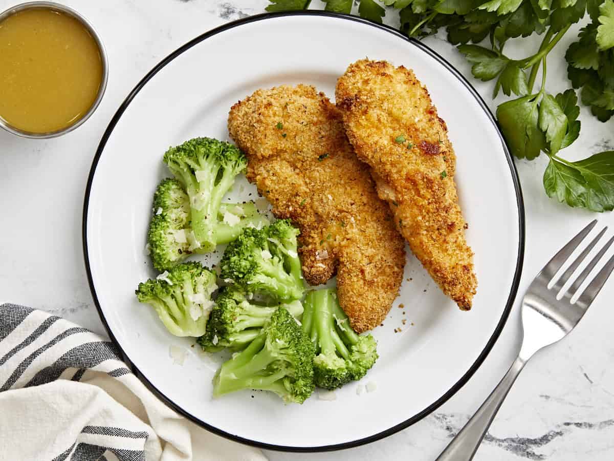 Overhead view of air fryer chicken tenders and steamed broccoli on a plate.