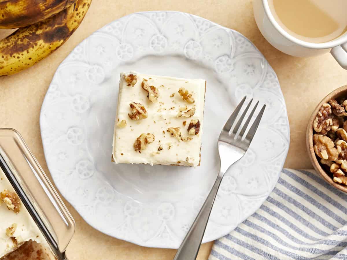 overhead view of a slice of banana cake on a white plate with a fork.