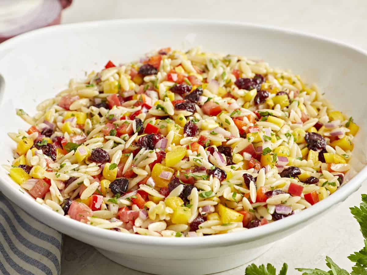 Side view of orzo pasta salad in a white serving bowl.