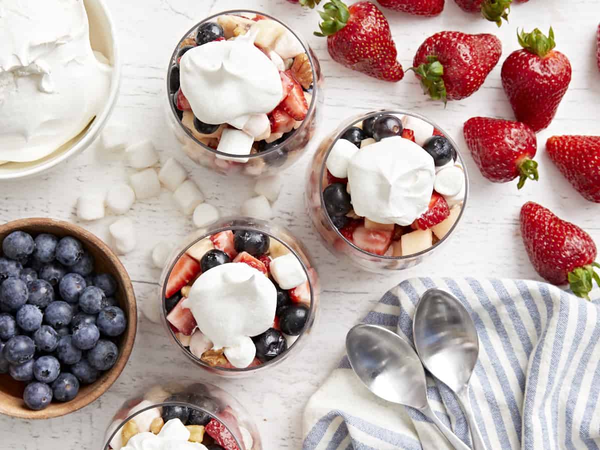 overhead view of servings of red white and blue fruit salad in stemless wine glasses with cool whip.