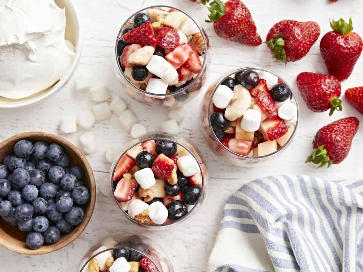 overhead view of servings of red white and blue fruit salad in stemless wine glasses.