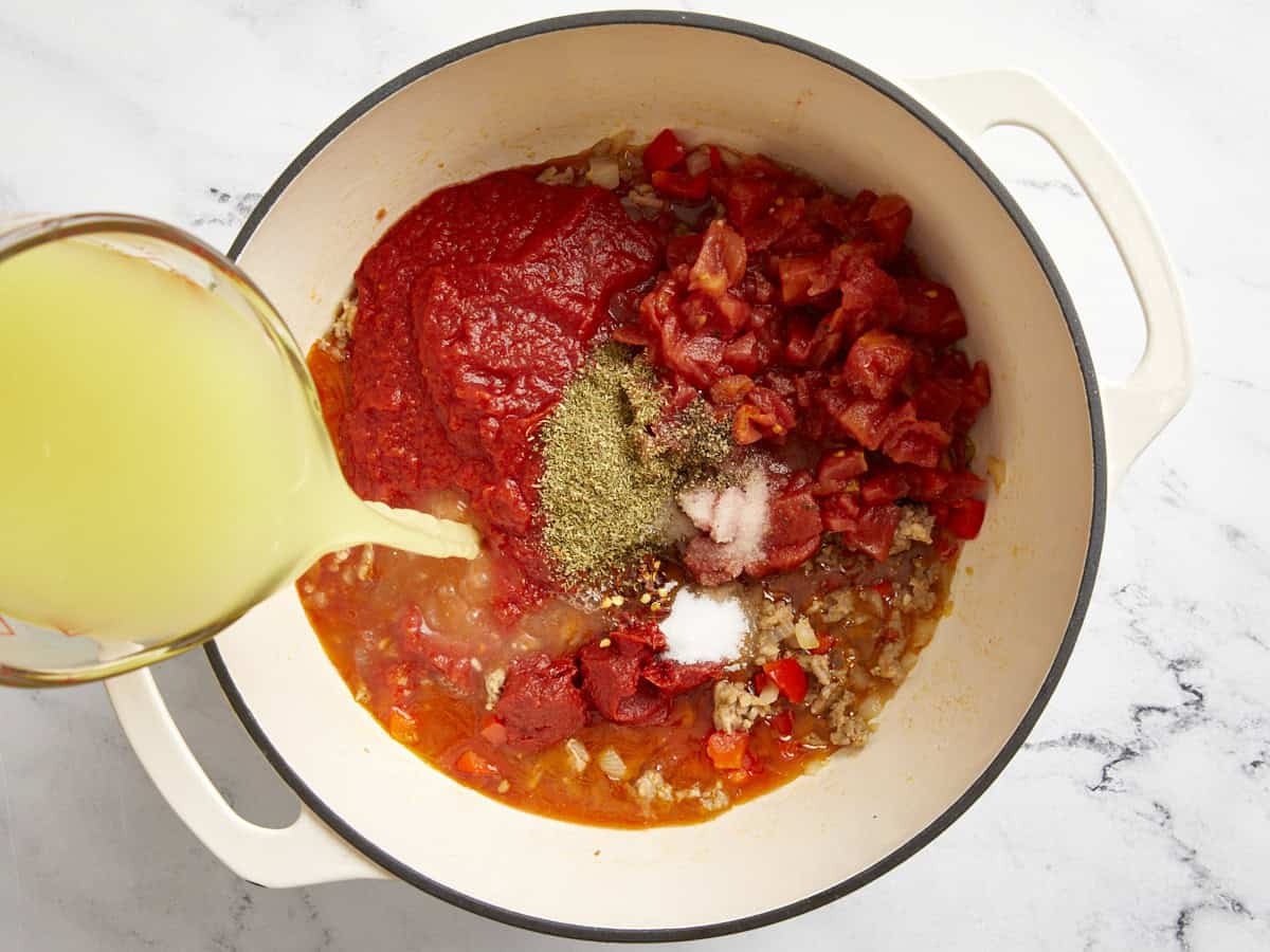 Tomatoes, spices, and chicken broth added to soup pot.