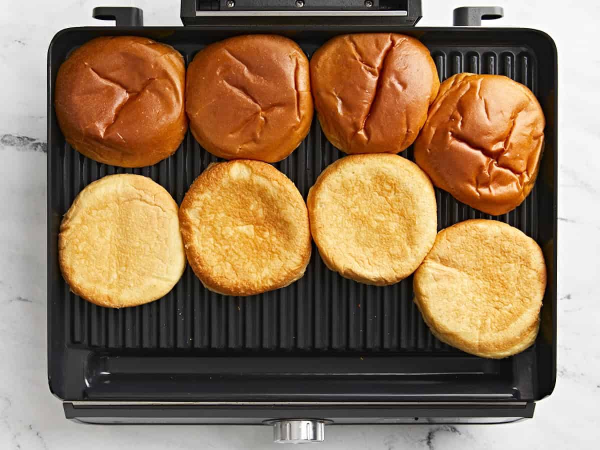 Toasting hamburger buns on a grill.