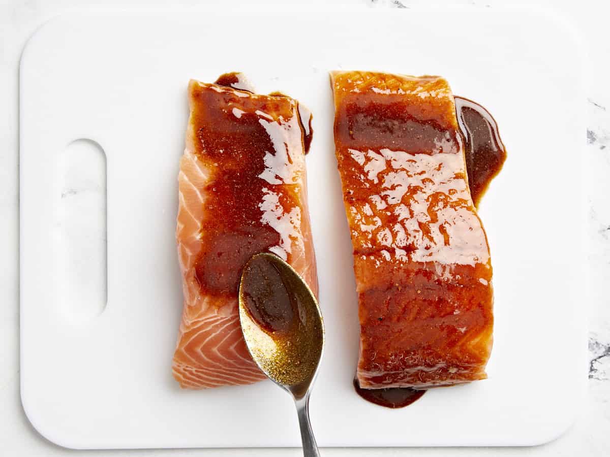 spooning marinade over salmon filets.