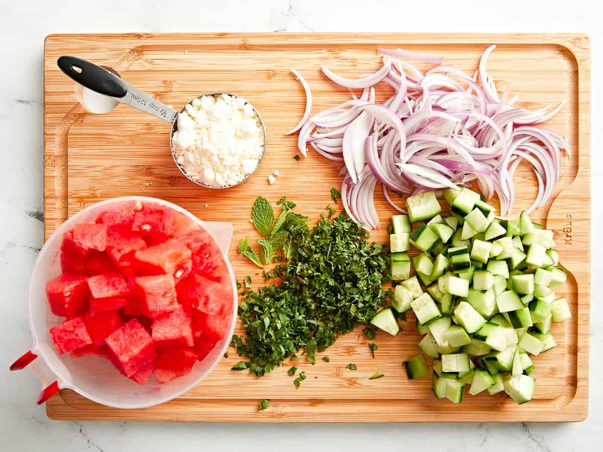mise en place for watermelon and feta salad on a wood cutting board.