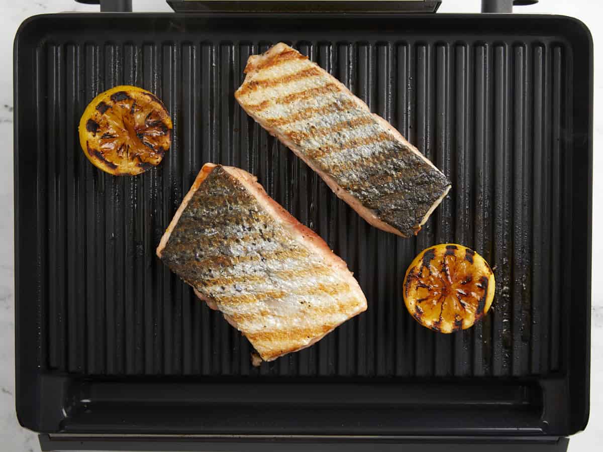 partially grilled salmon fillets on a grill pan.