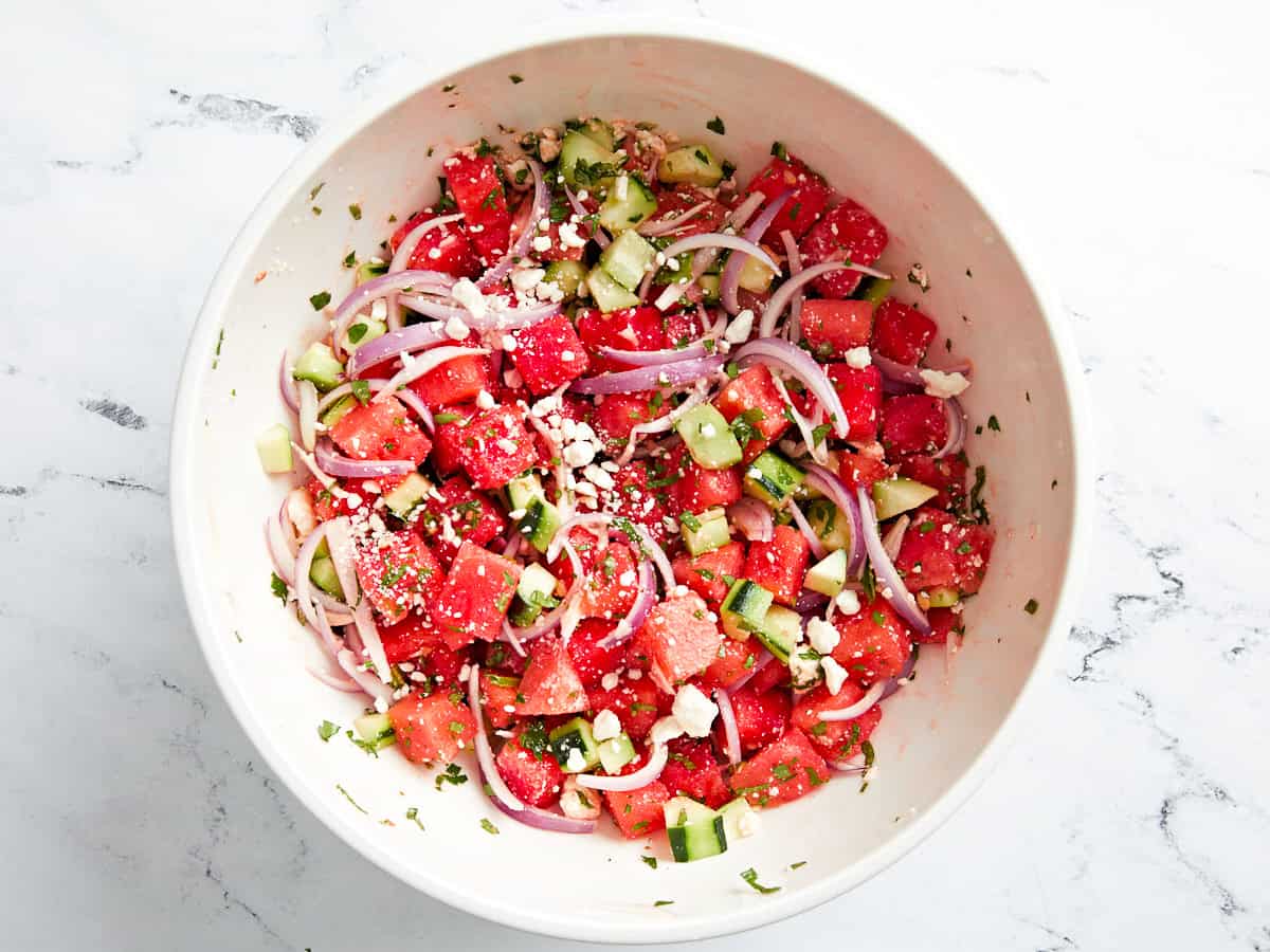 tossed watermelon and feta salad in a white bowl.