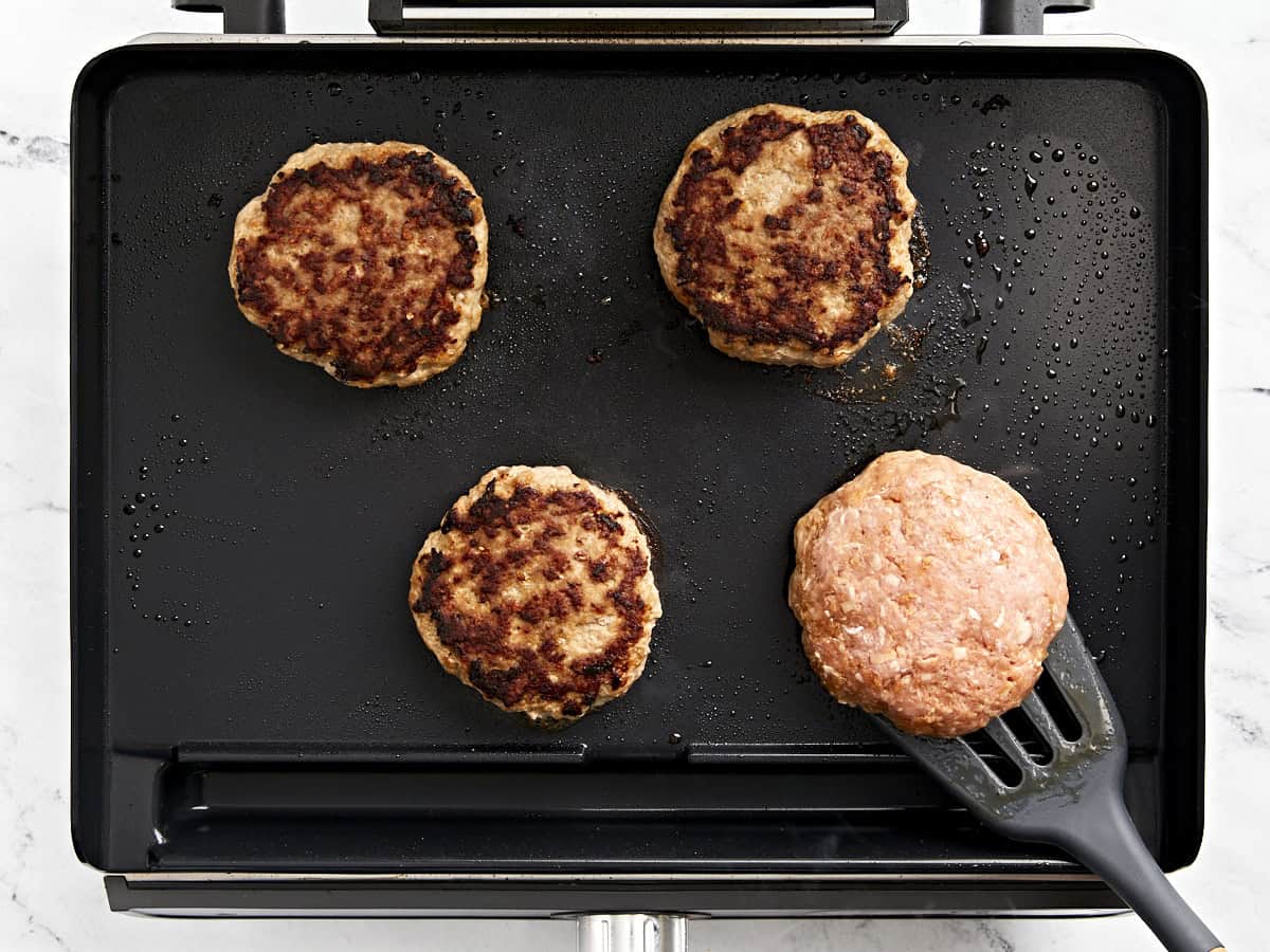 flipping turkey burgers on a grill pan.