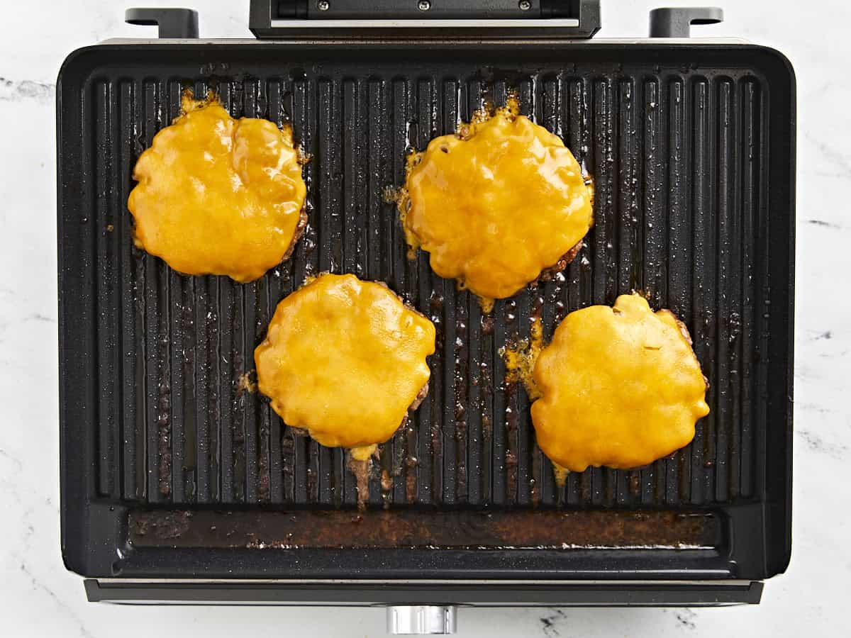 Hamburgers with melted cheese on top on the grill.