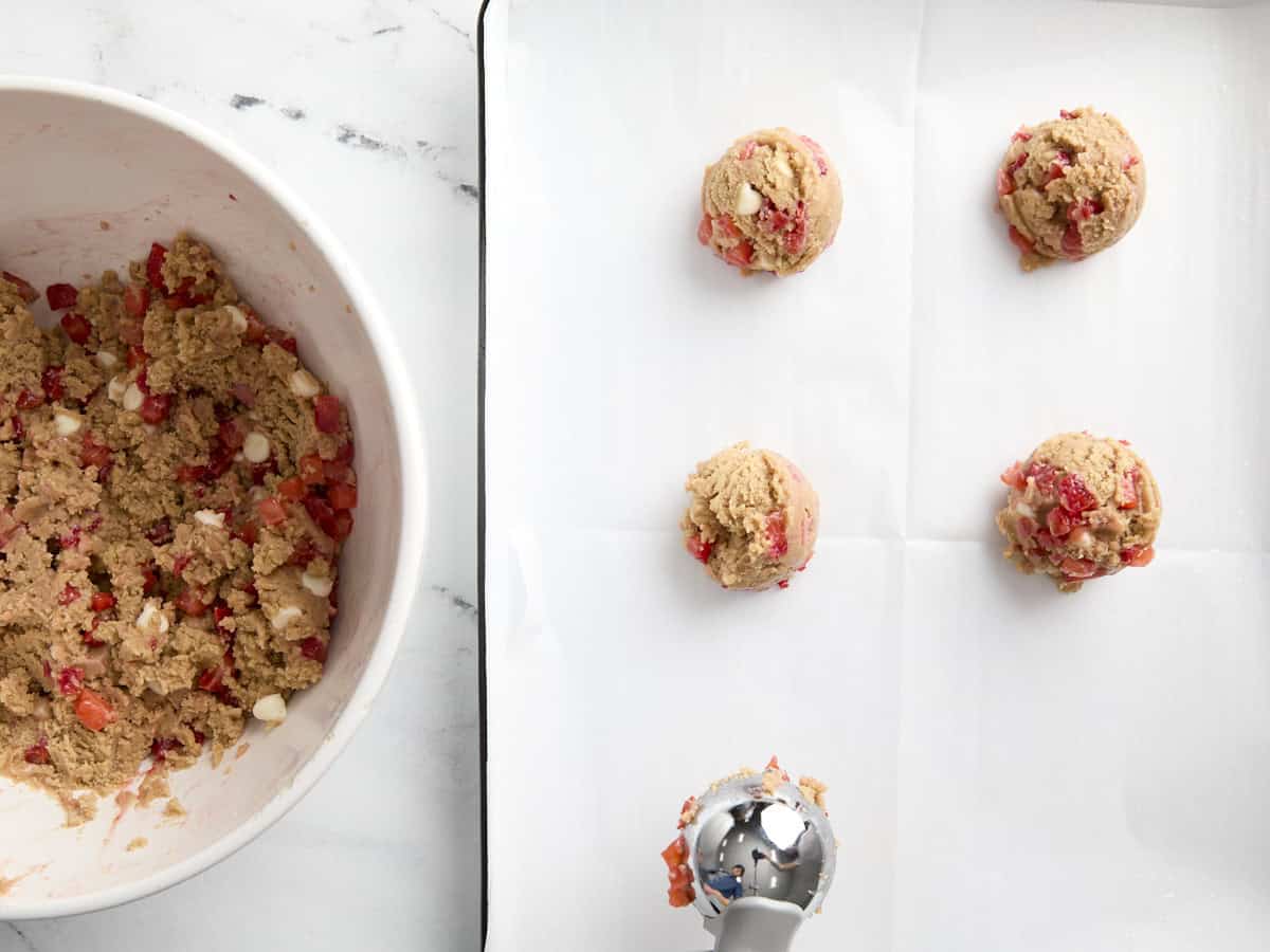 placing cookie dough balls with a cookie scoop on a parchment-lined baking sheet.