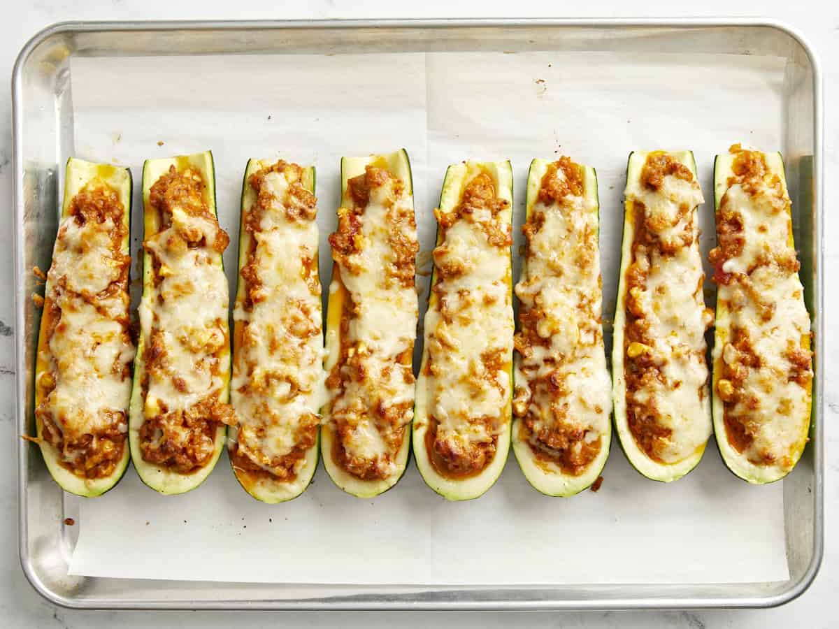 Cooked Zucchini boats on a parchment lined baking sheet.