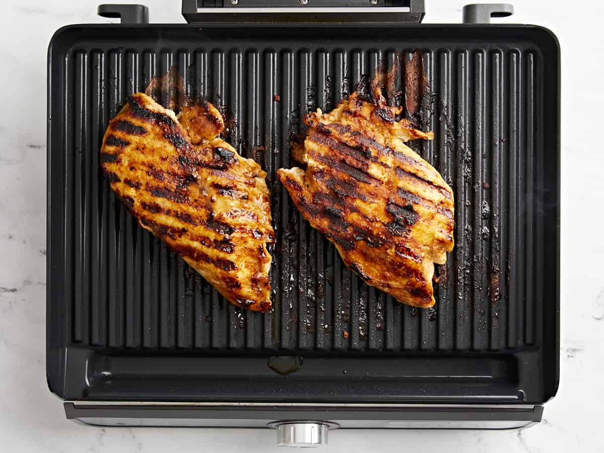 2 fully cooked chicken breasts on a grill.