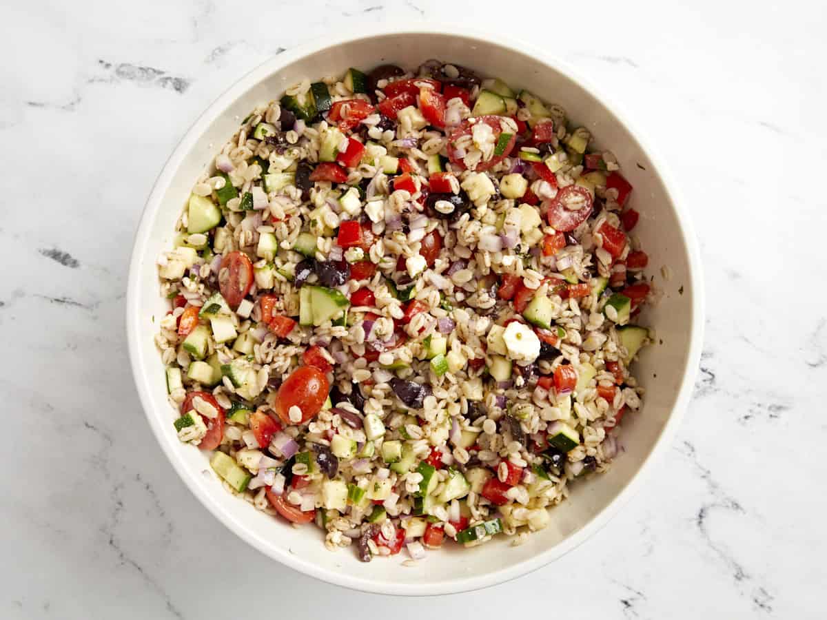 tossed barley salad in a white bowl.