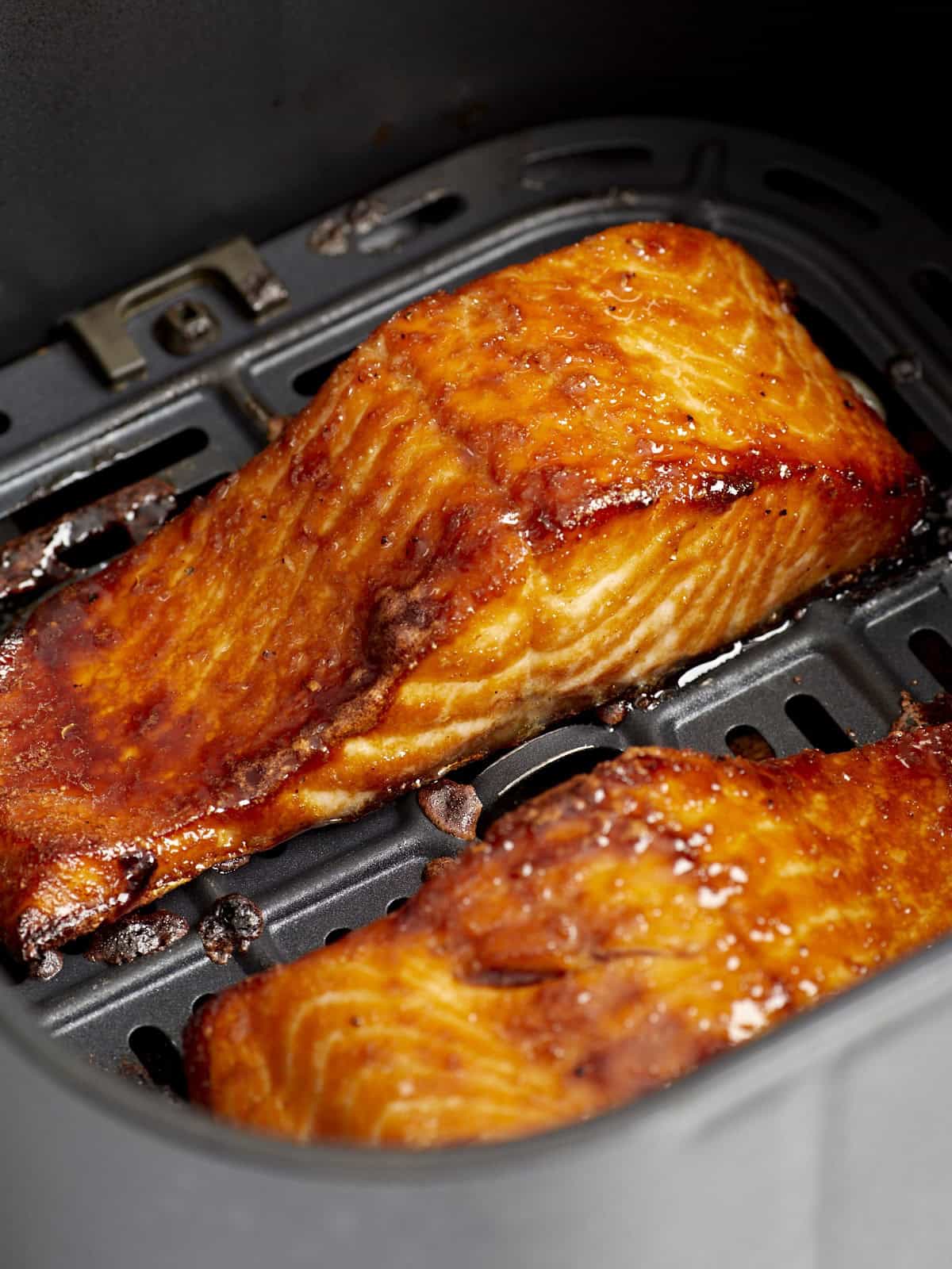 close up of air fryer salmon filets in an air fryer basket.