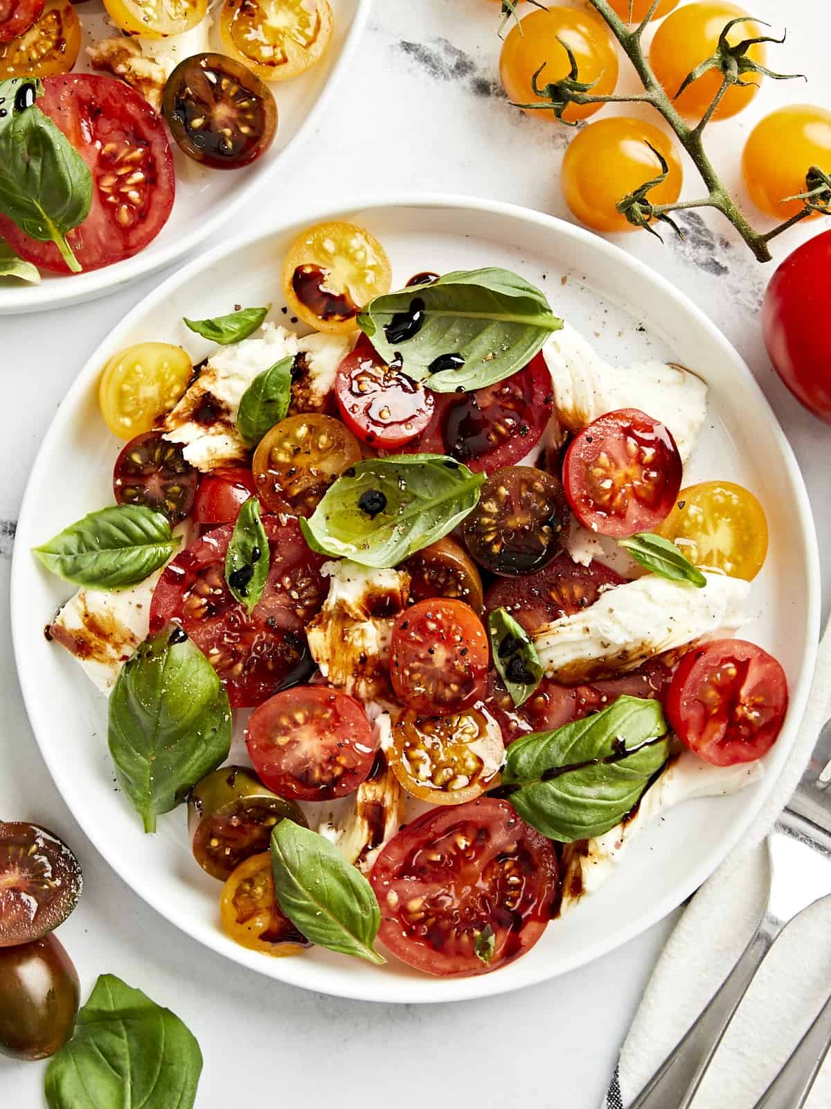 overhead view of a serving of caprese salad on a white plate with balsamic glaze.