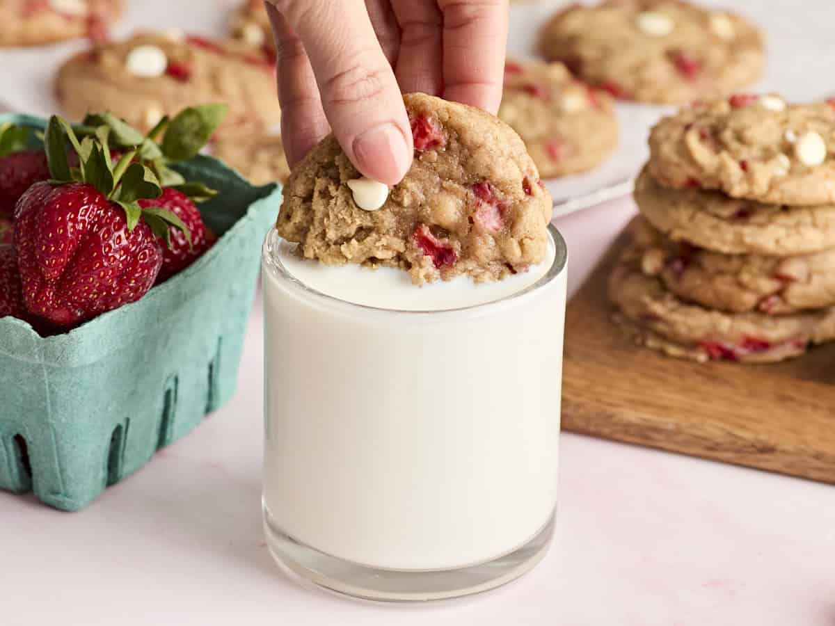 dipping a strawberry cookie into a glass of milk.