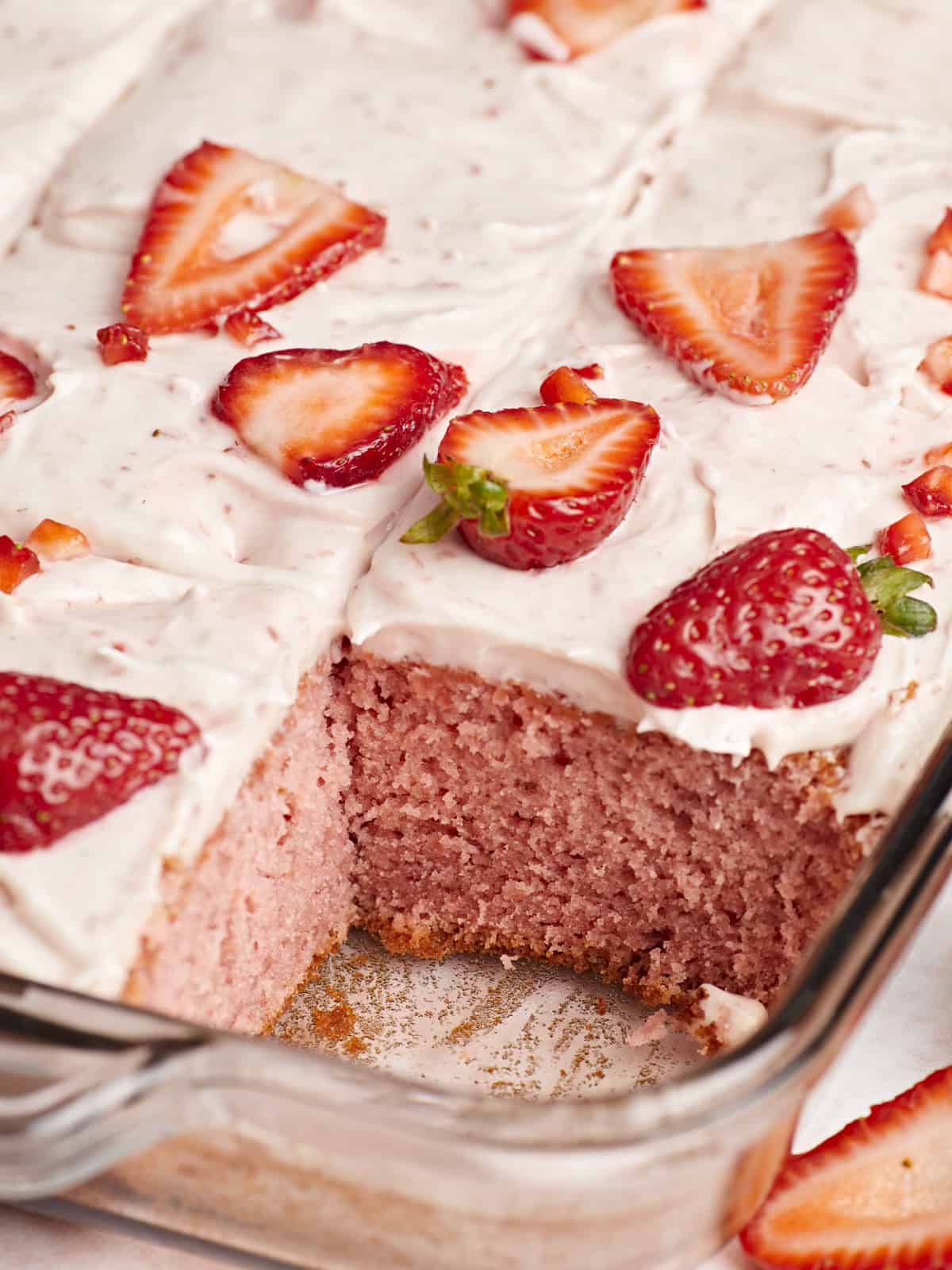 Side view of strawberry sheet cake with one slice removed.