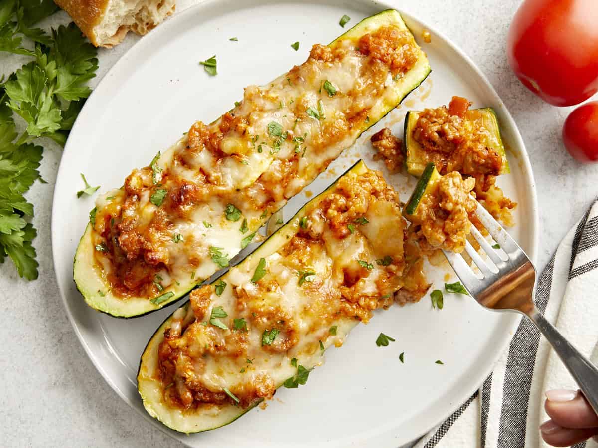 Overhead view of two Zucchini boats on a plate with a fork picking some up.