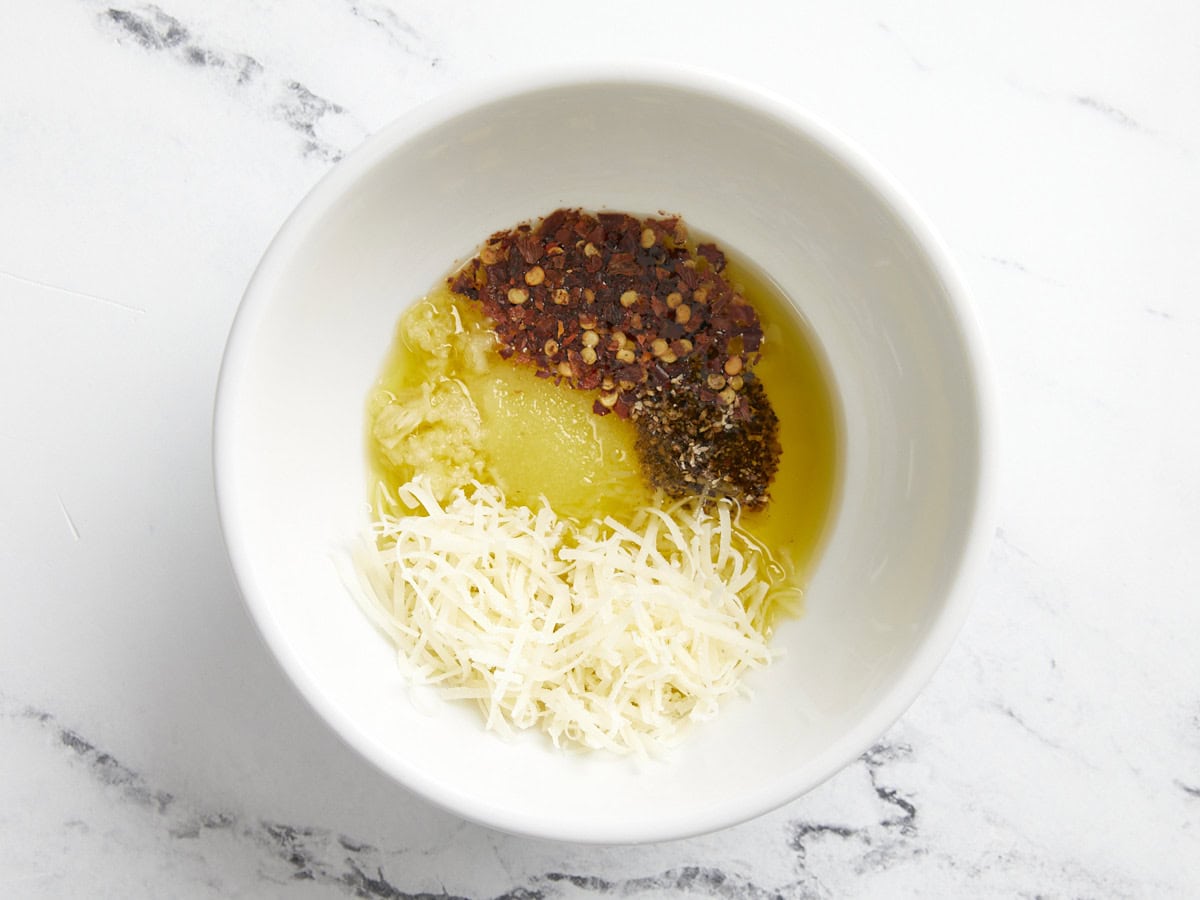 Olive oil, salt, Parmesan cheese, minced garlic, pepper, and chili flakes in a small bowl for grilled cabbage marinade.
