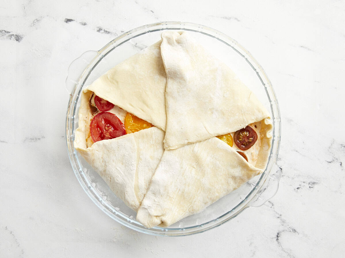 Tomato pie in a glass pie dish ready to be baked.