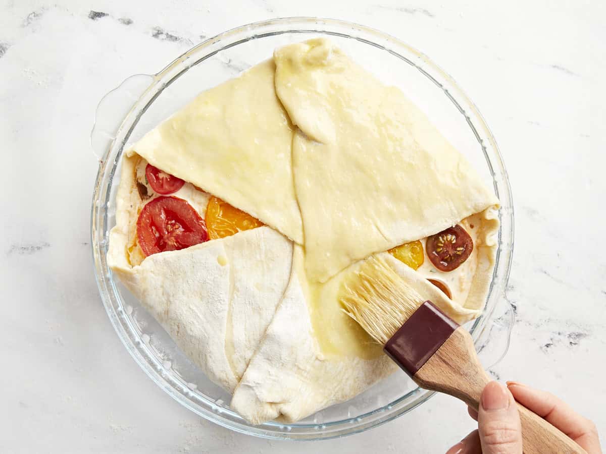 A brush egg washing a tomato pie before baking.