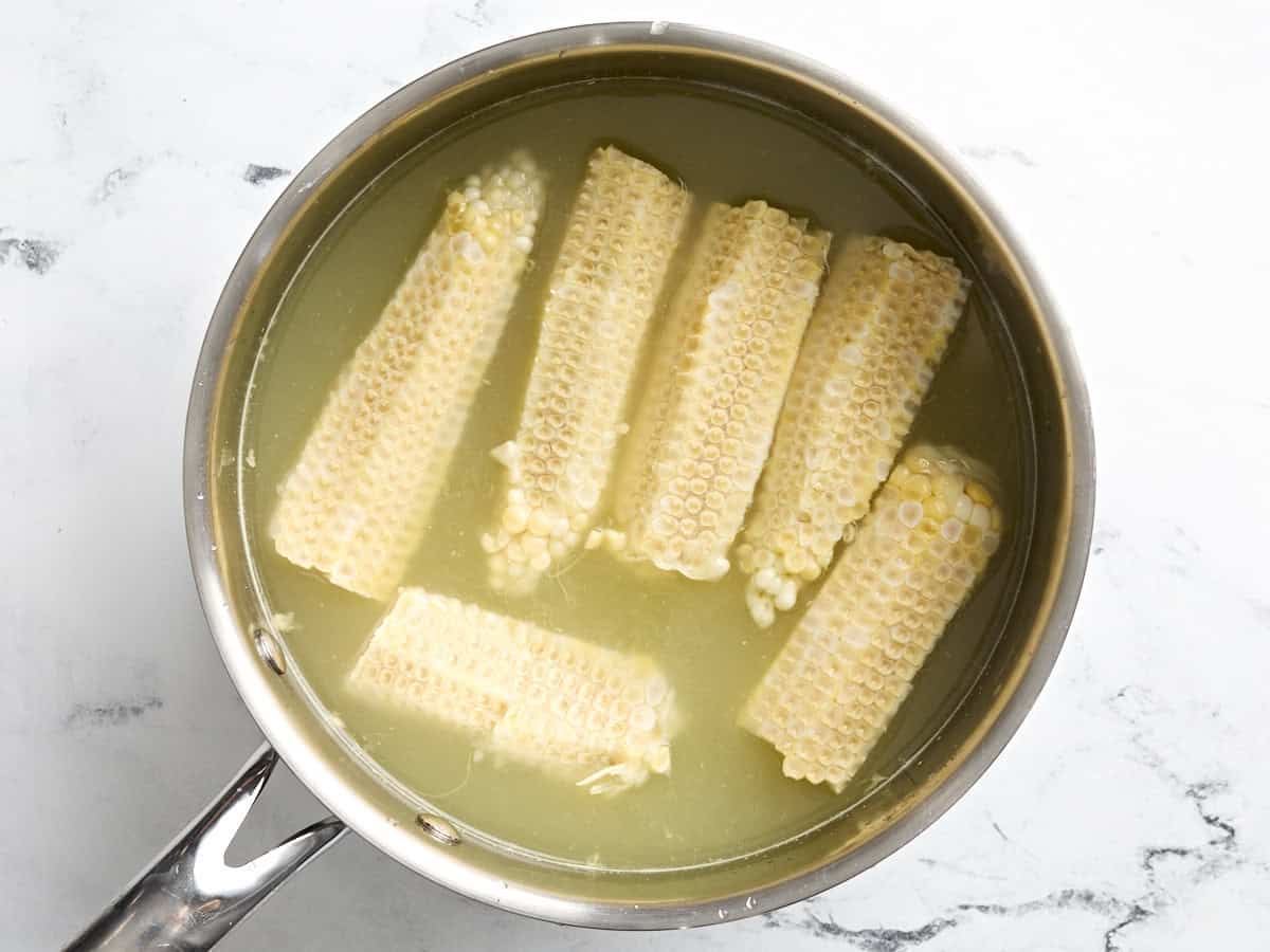 Bare corn cobs and vegetable broth in a pot.