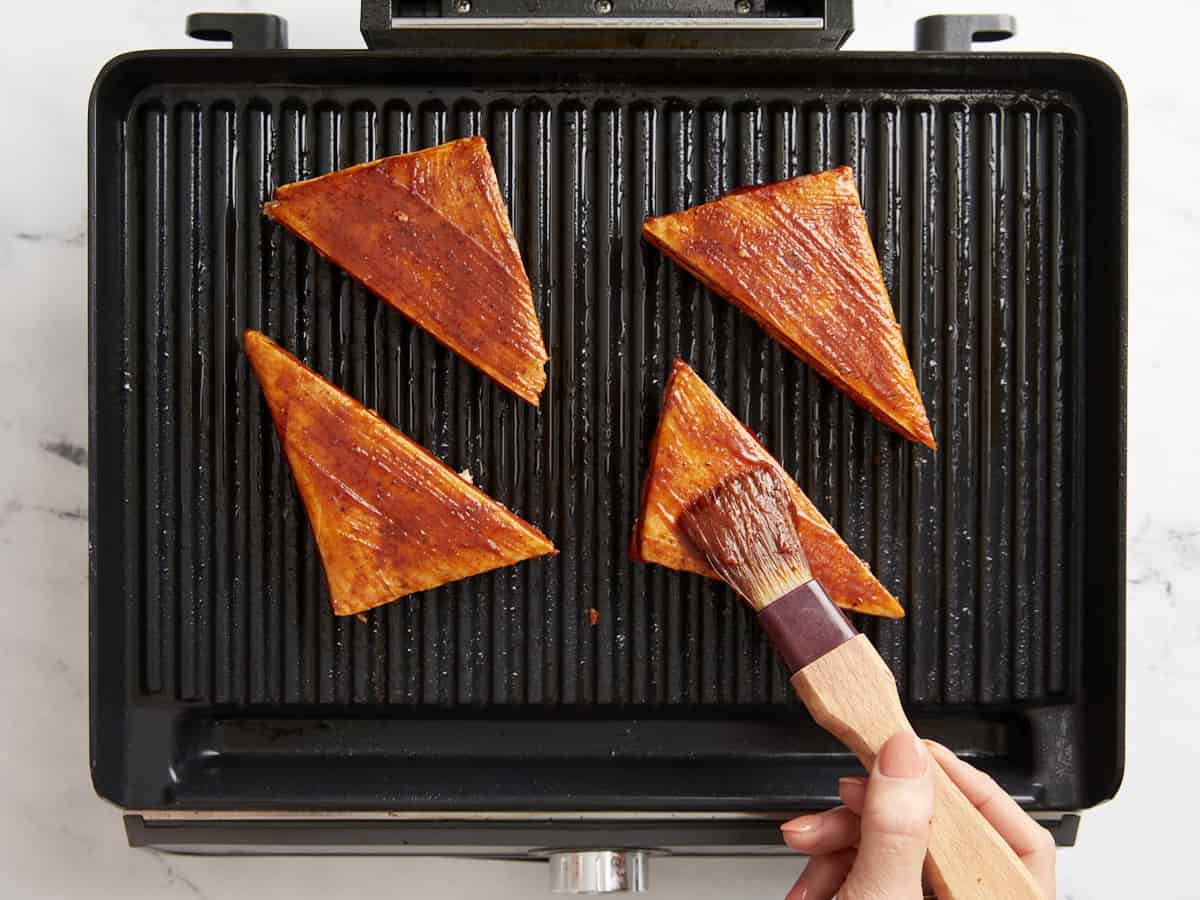 BBQ grilled tofu being brushed with BBQ sauce.