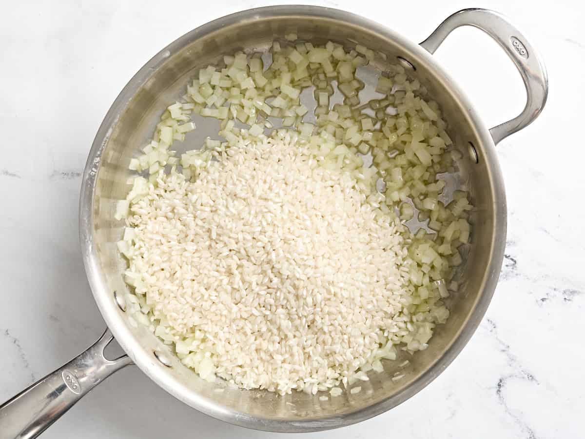 Arborio rice added to diced onions in a skillet.