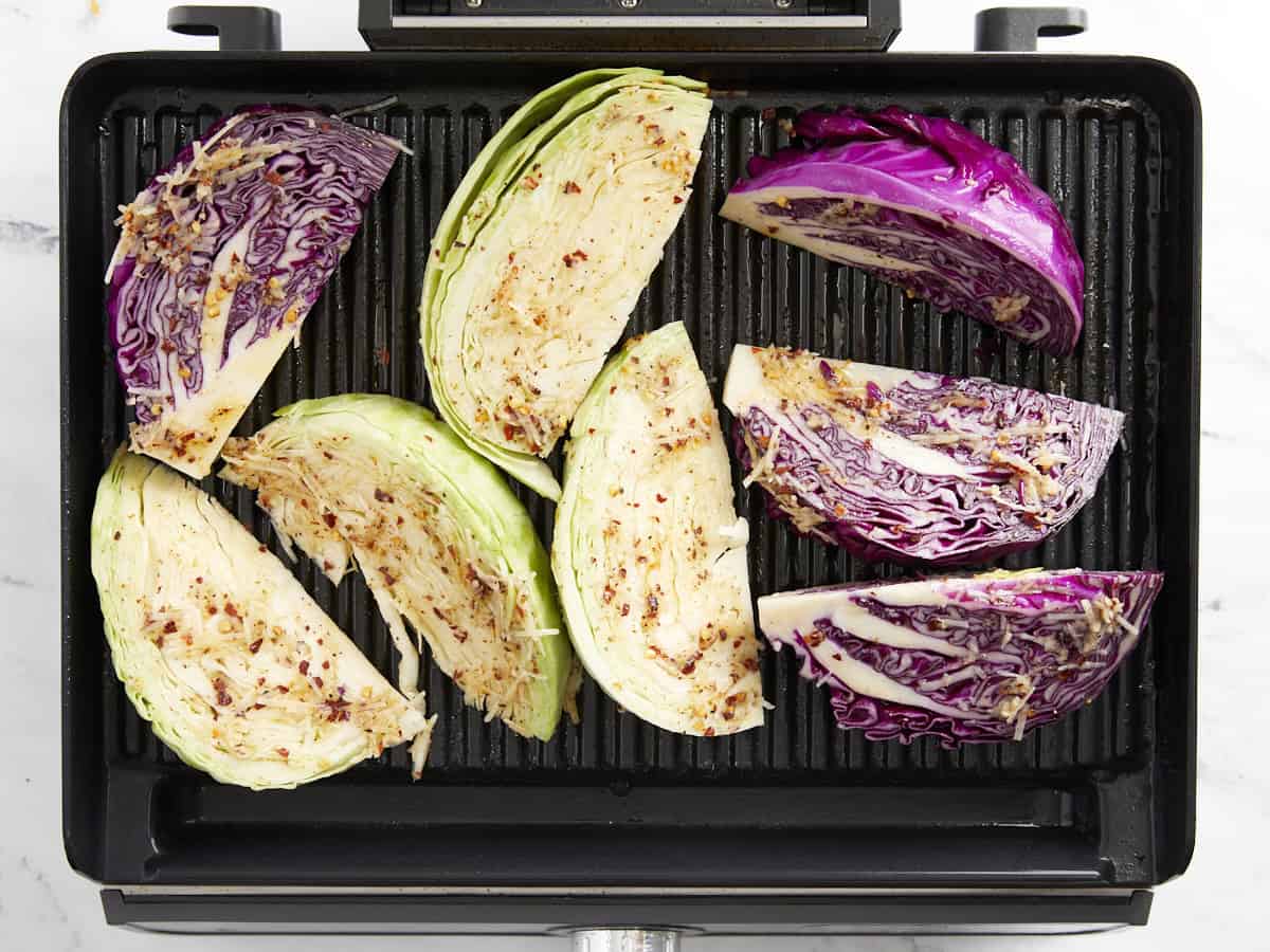 Marinaded green and red cabbage wedges on a grill.