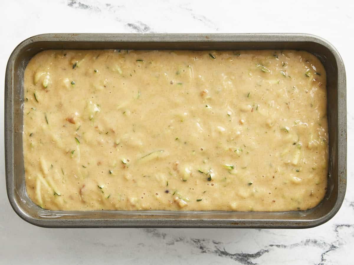 Zucchini bread batter added to a loaf pan.