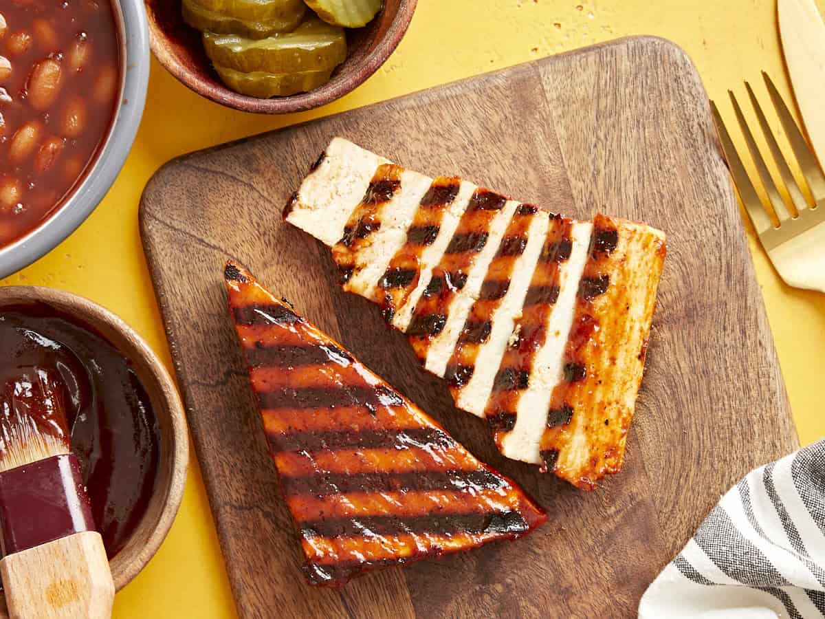 Sliced BBQ grilled tofu on a chopping board.