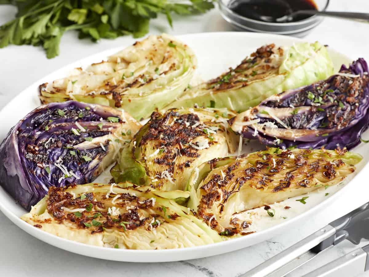 Side view of grilled cabbage wedges topped with balsamic glaze, Parmesan, and fresh parsley.