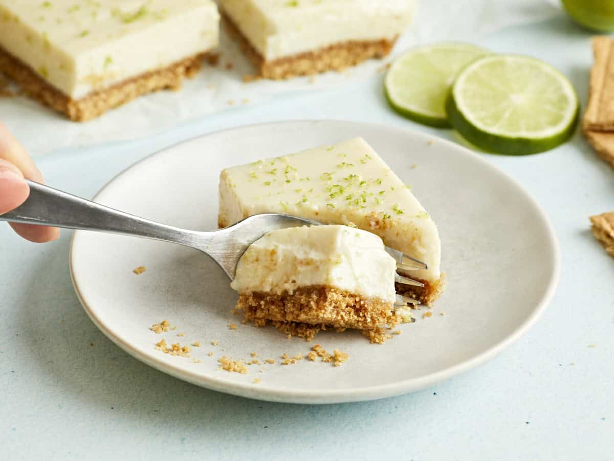 A key lime pie bar being sliced in half by a fork.