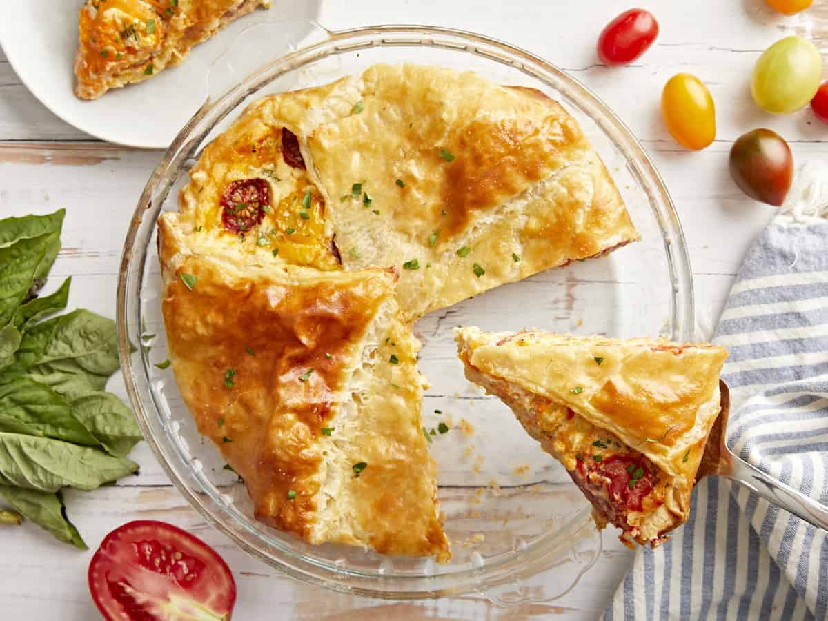 Tomato pie in a baking dish with a slice being served.