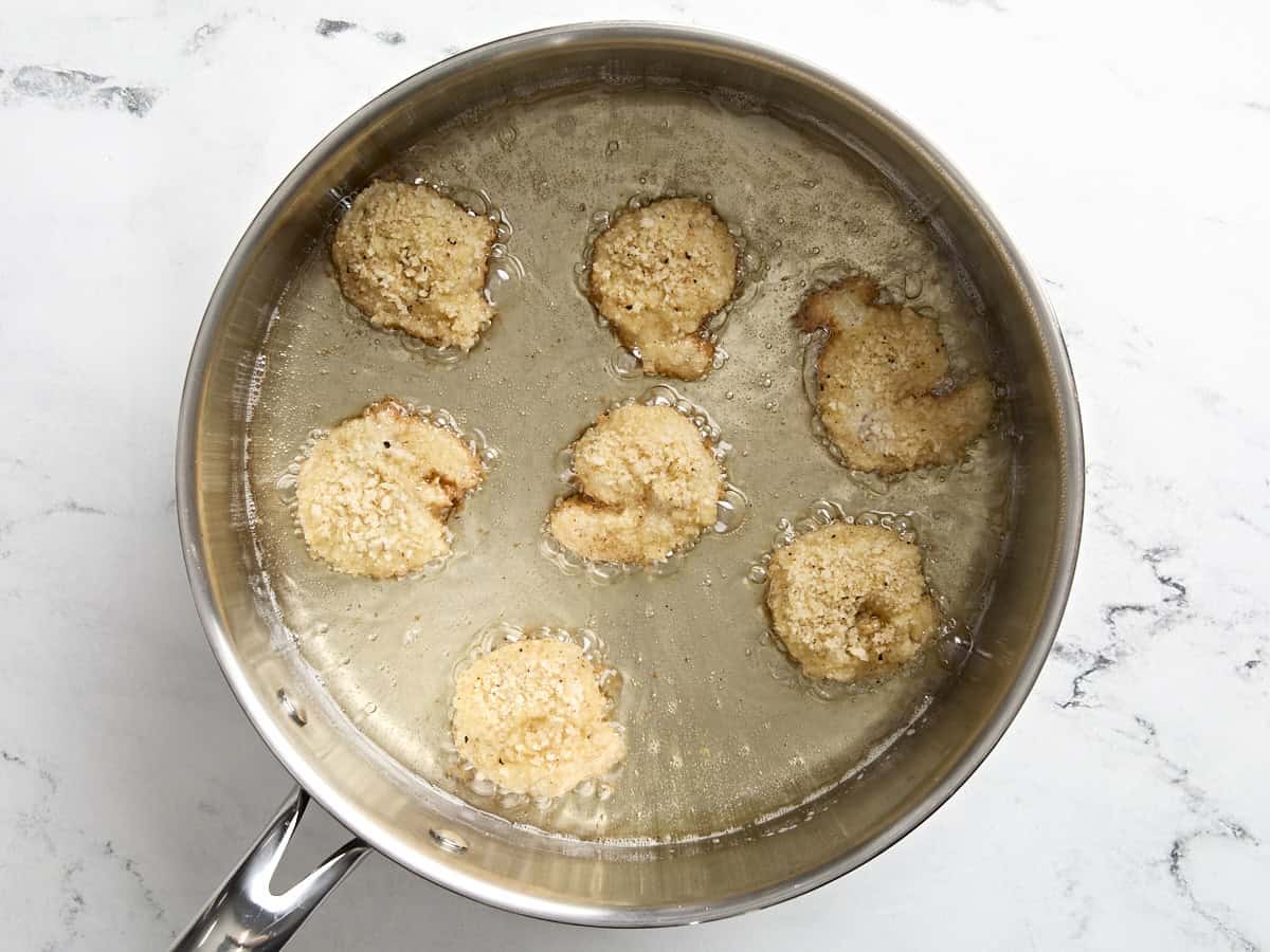 Breaded shrimp deep frying in a skillet