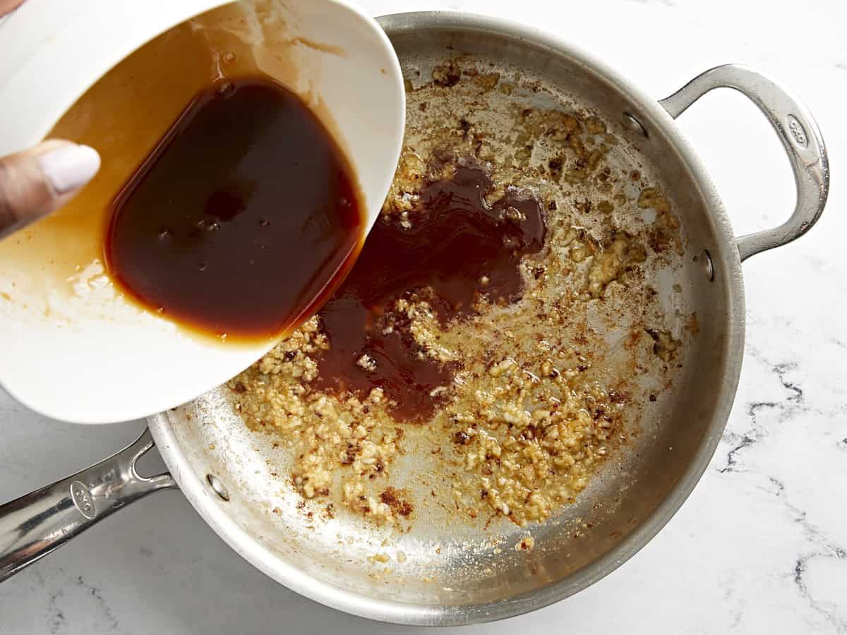 Honey garlic chicken sauce being added to skillet