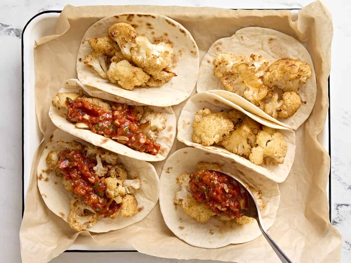 Cauliflower tacos with romesco sauce on a parchment lined baking sheet