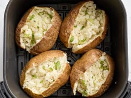 Overhead view of air fryer baked potatoes in an air fryer basket.