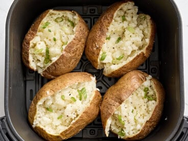 Overhead view of air fryer baked potatoes in an air fryer basket.