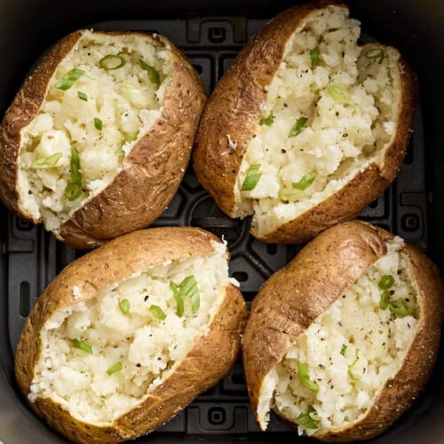 Overhead view of air fryer baked potatoes in an air fryer basket.