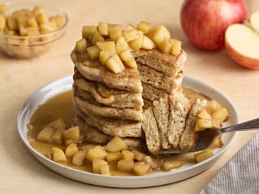 Front view of a stack of apple cinnamon pancakes with fork lifting some out.